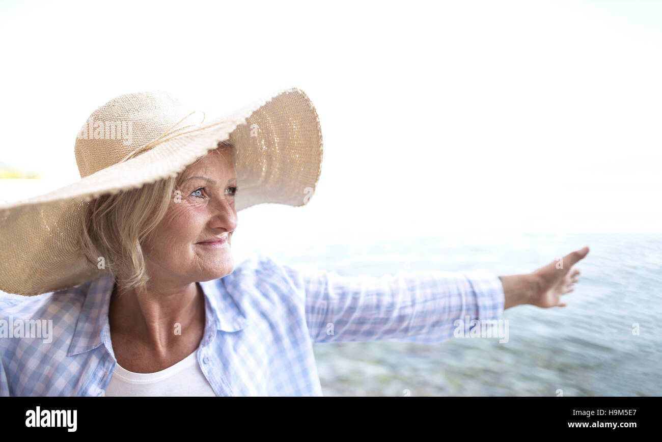 Happy mature woman wearing straw hat on the beach Stock Photo - Alamy