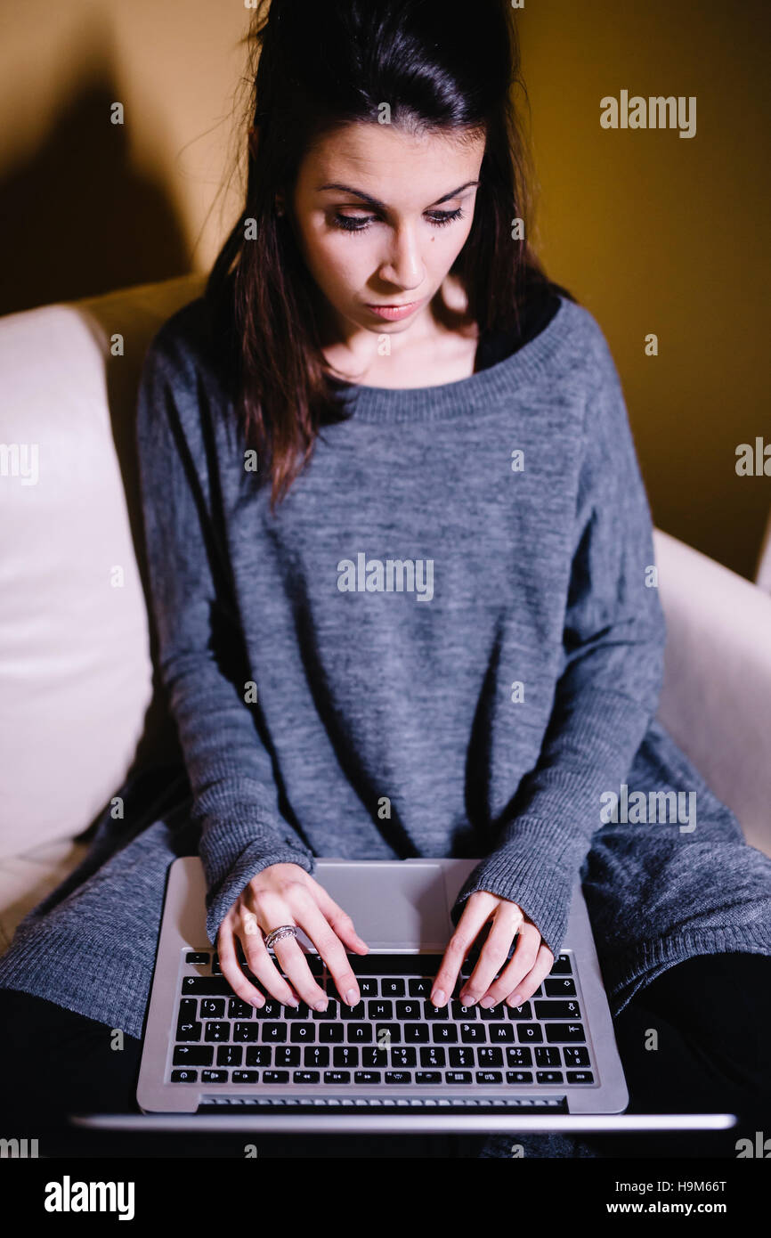 Young woman sitting on the couch using laptop Stock Photo - Alamy