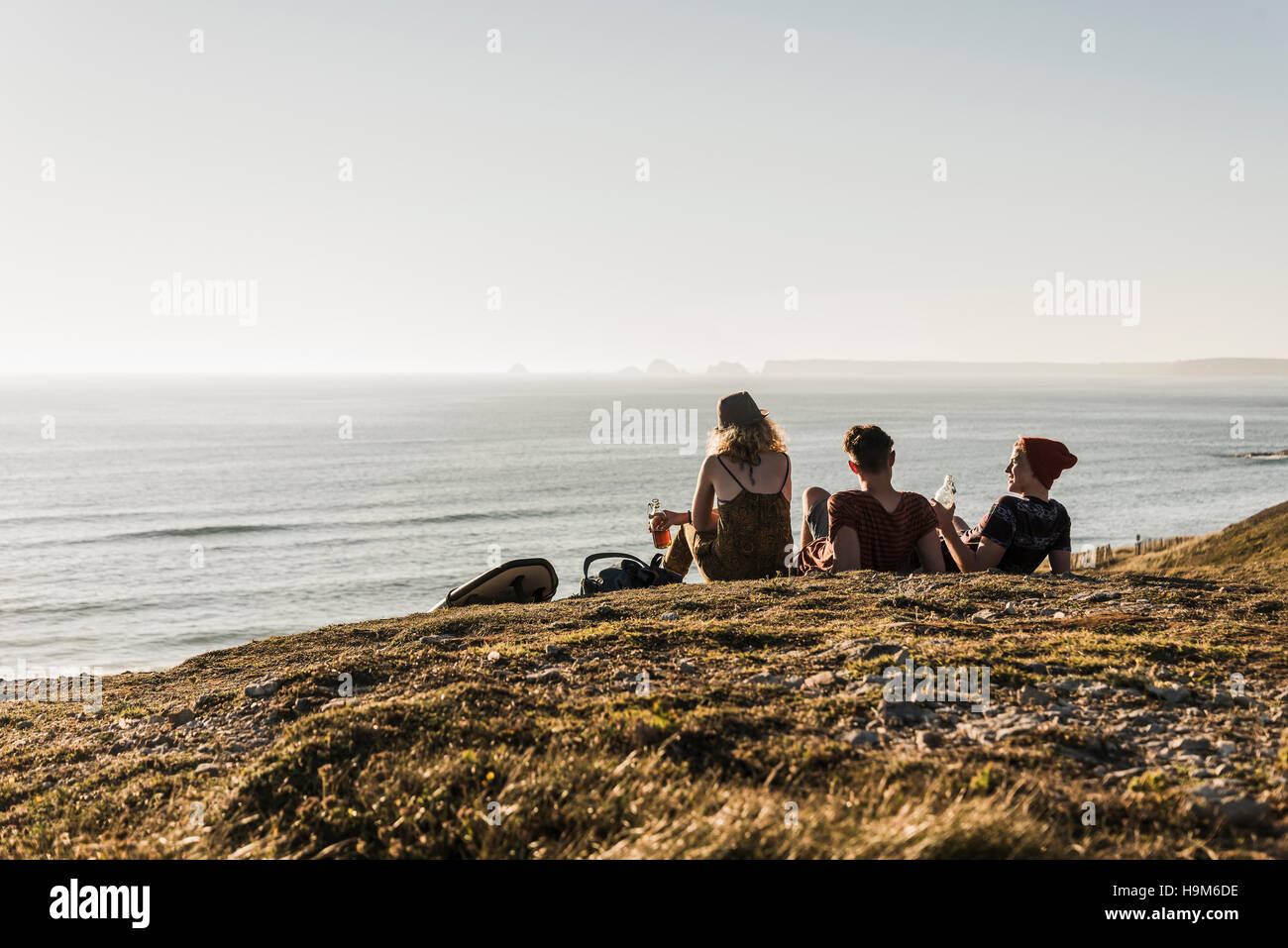 Back view of three friends relaxing at seaside Stock Photo