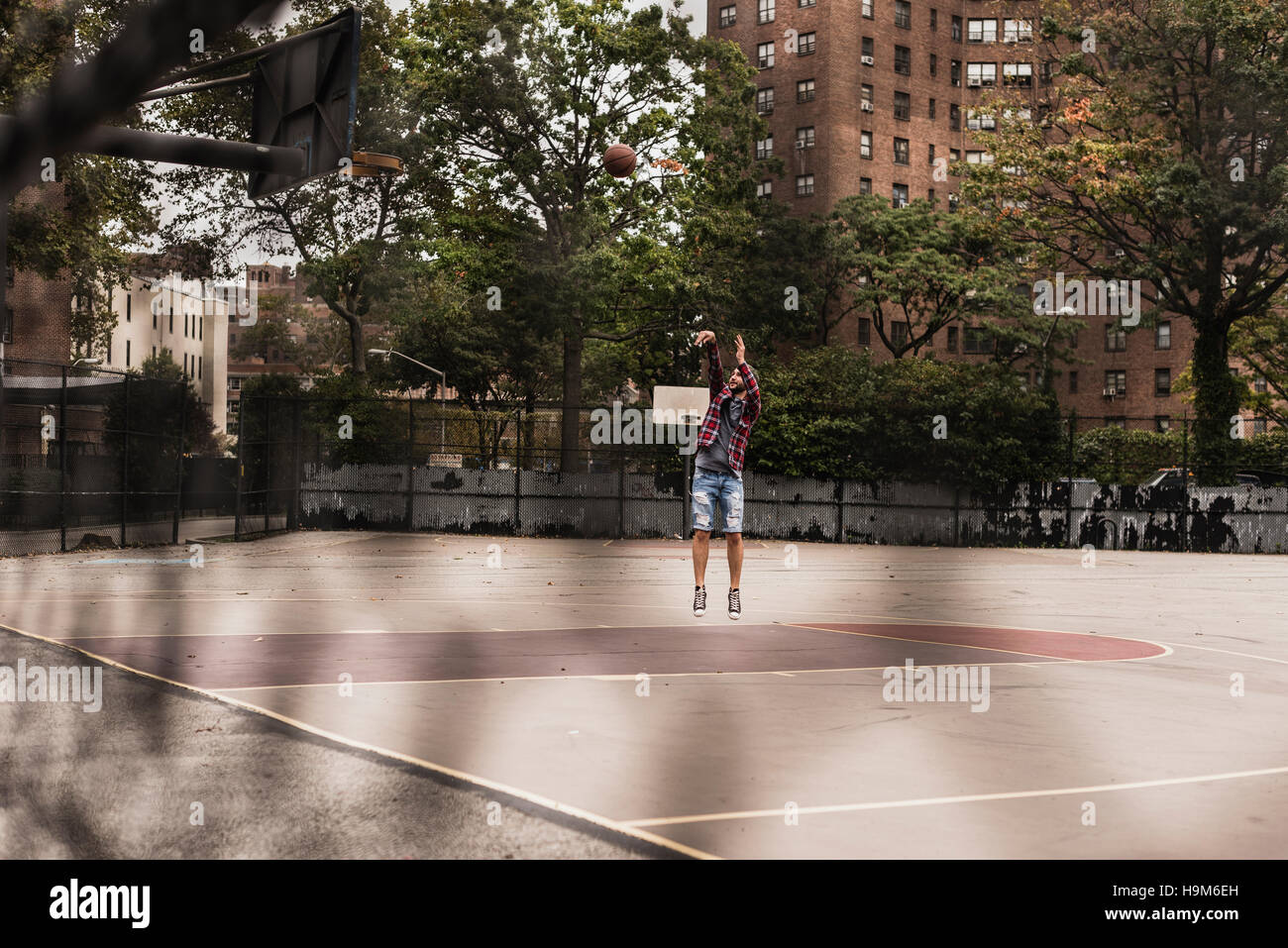 Young man playing basketball on an outdoor court Stock Photo