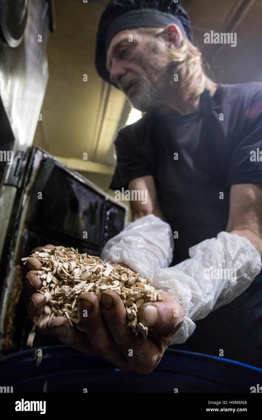 Fish smoker putting beechwood chips into smoker Stock Photo Alamy
