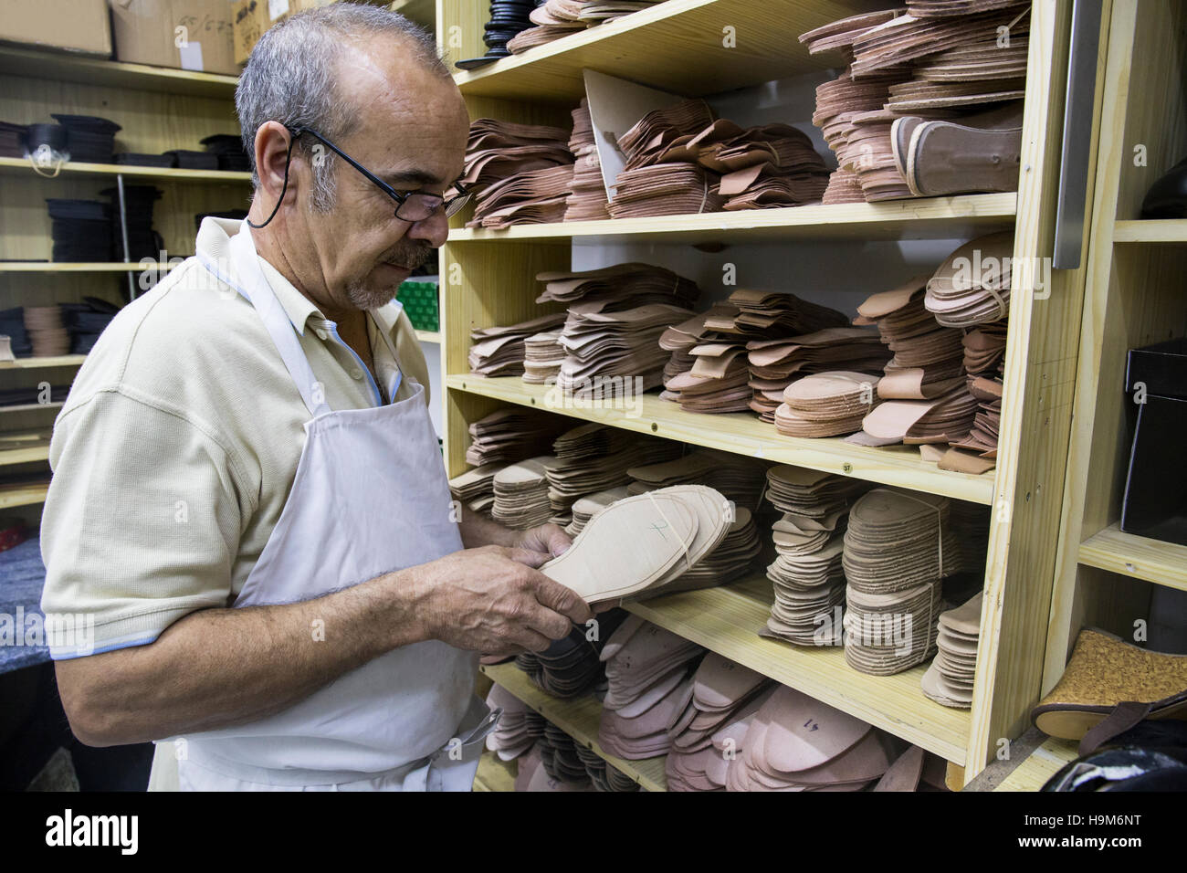 Shoemaker selecting shoe soles from a shelf in his workshop Stock Photo ...