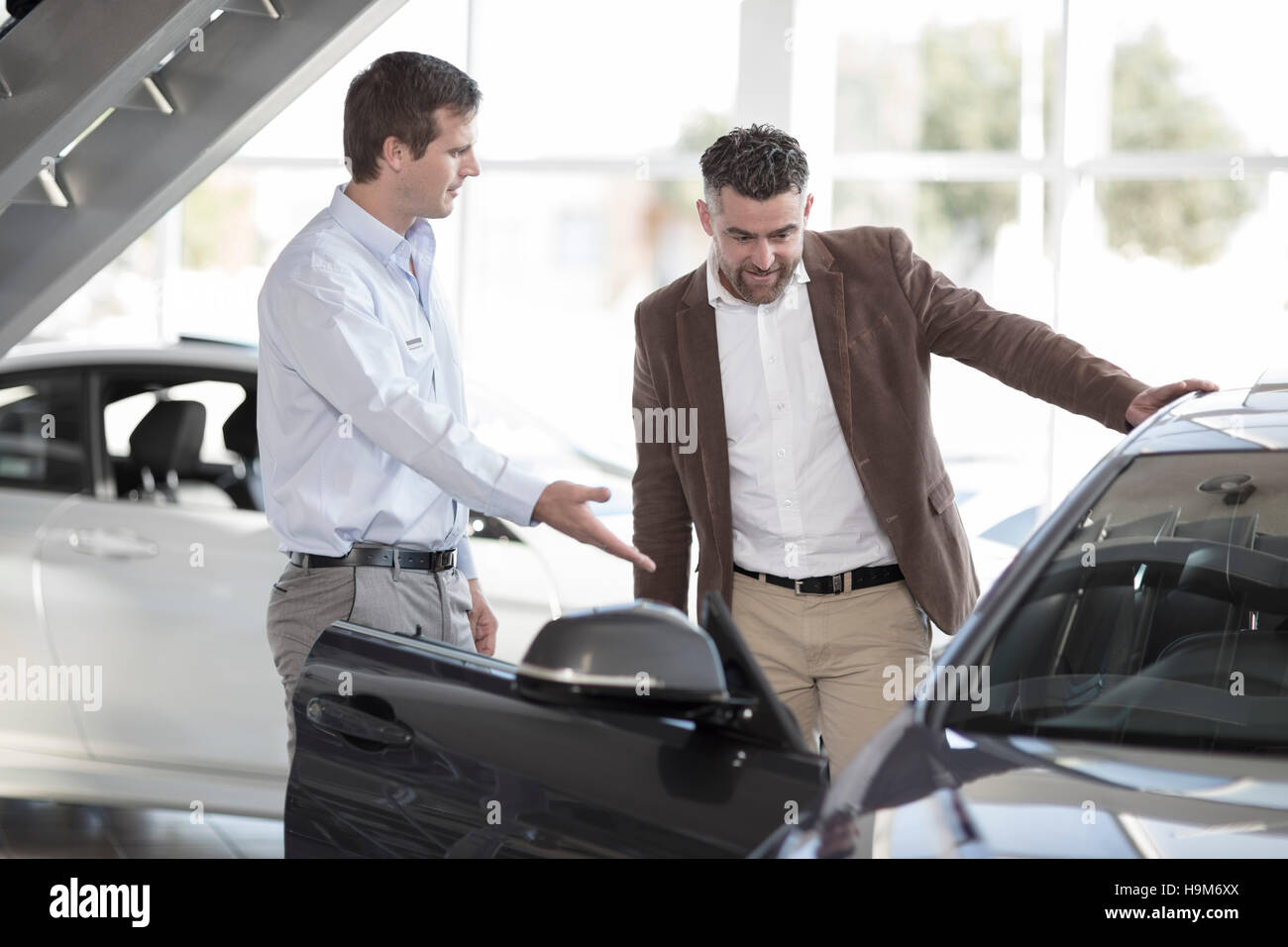 Car dealer talking to client in showroom Stock Photo Alamy