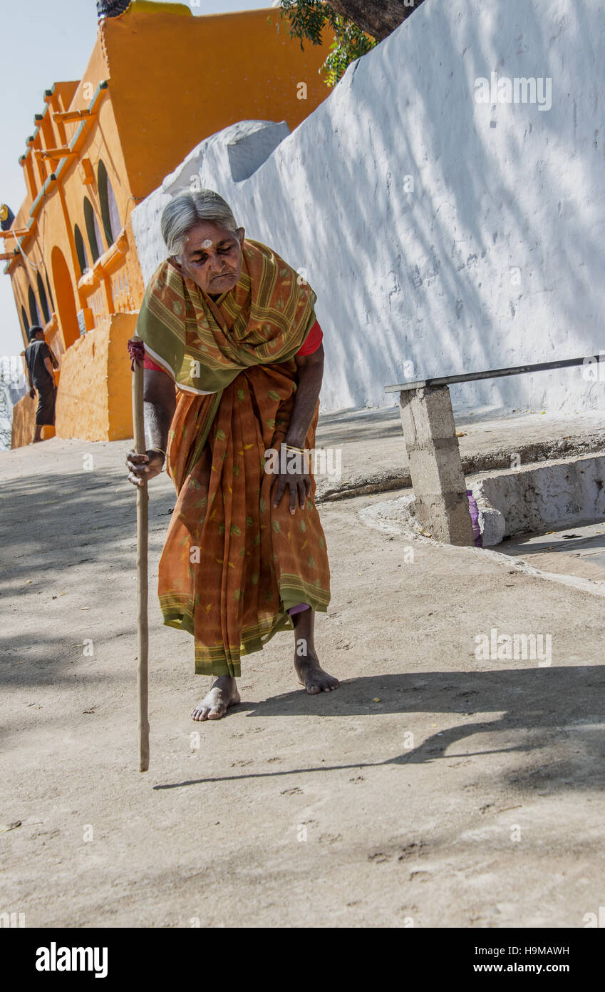 Elderly Indian blind woman walking with the help of a cane near
