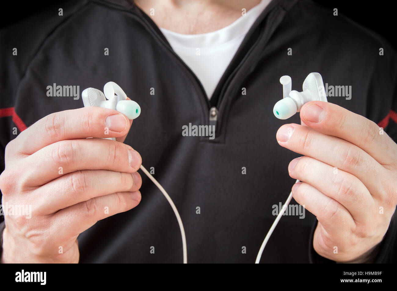 Runner assumes modern waterproof wireless headphones. Concept of technology in sport Stock Photo