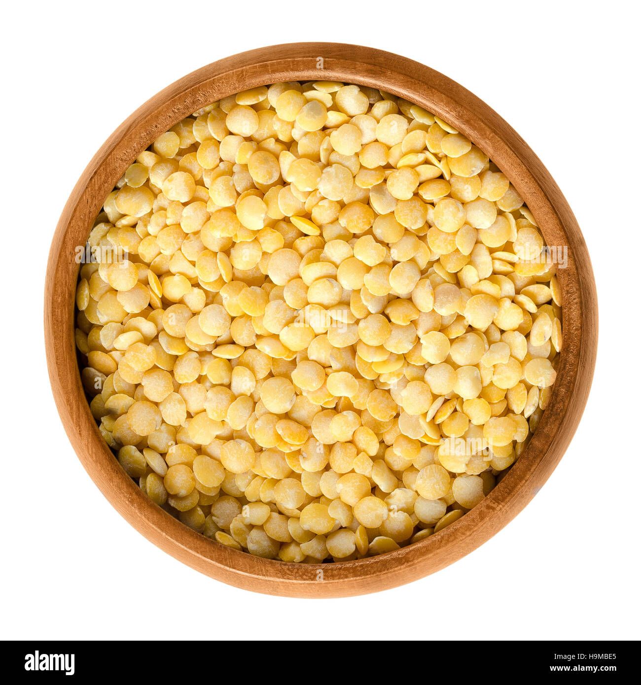 Yellow lentils in wooden bowl on white background. Seeds of Lens culinaris, edible raw pulses of the legume family. Stock Photo