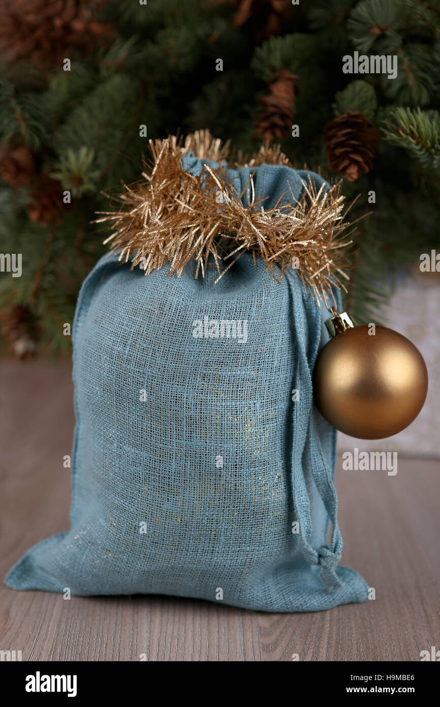 Soft blue Santa bag in Christmas time. Woven linen fabric pouch. Gifts bag decorated with gold ball. Stock Photo