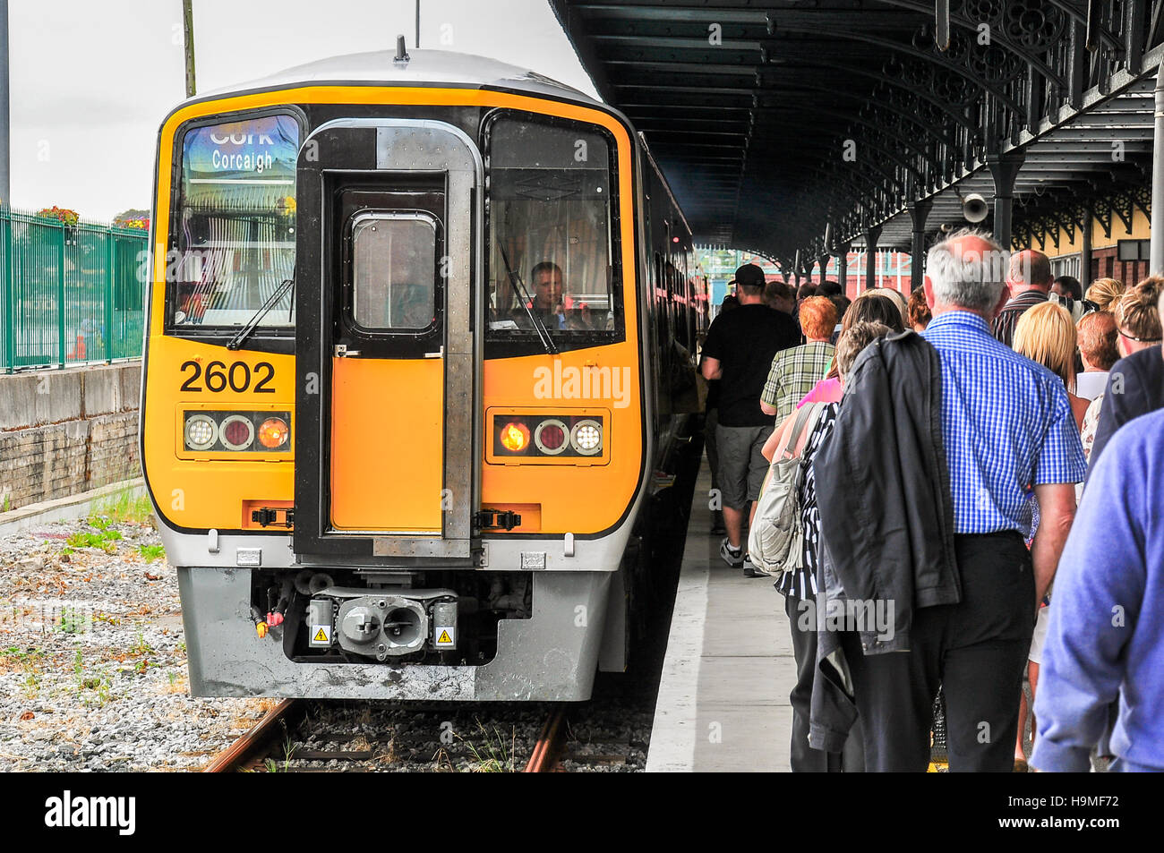Large group of people queue to board the train from the coastal town of Cobh to Cork, Ireland. Stock Photo