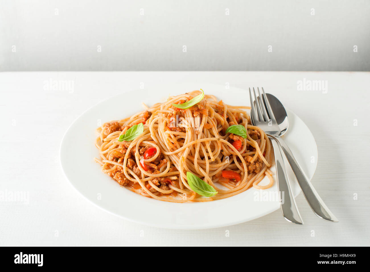Spaghetti with Bolognese sauce and basil served on a white plate Stock Photo