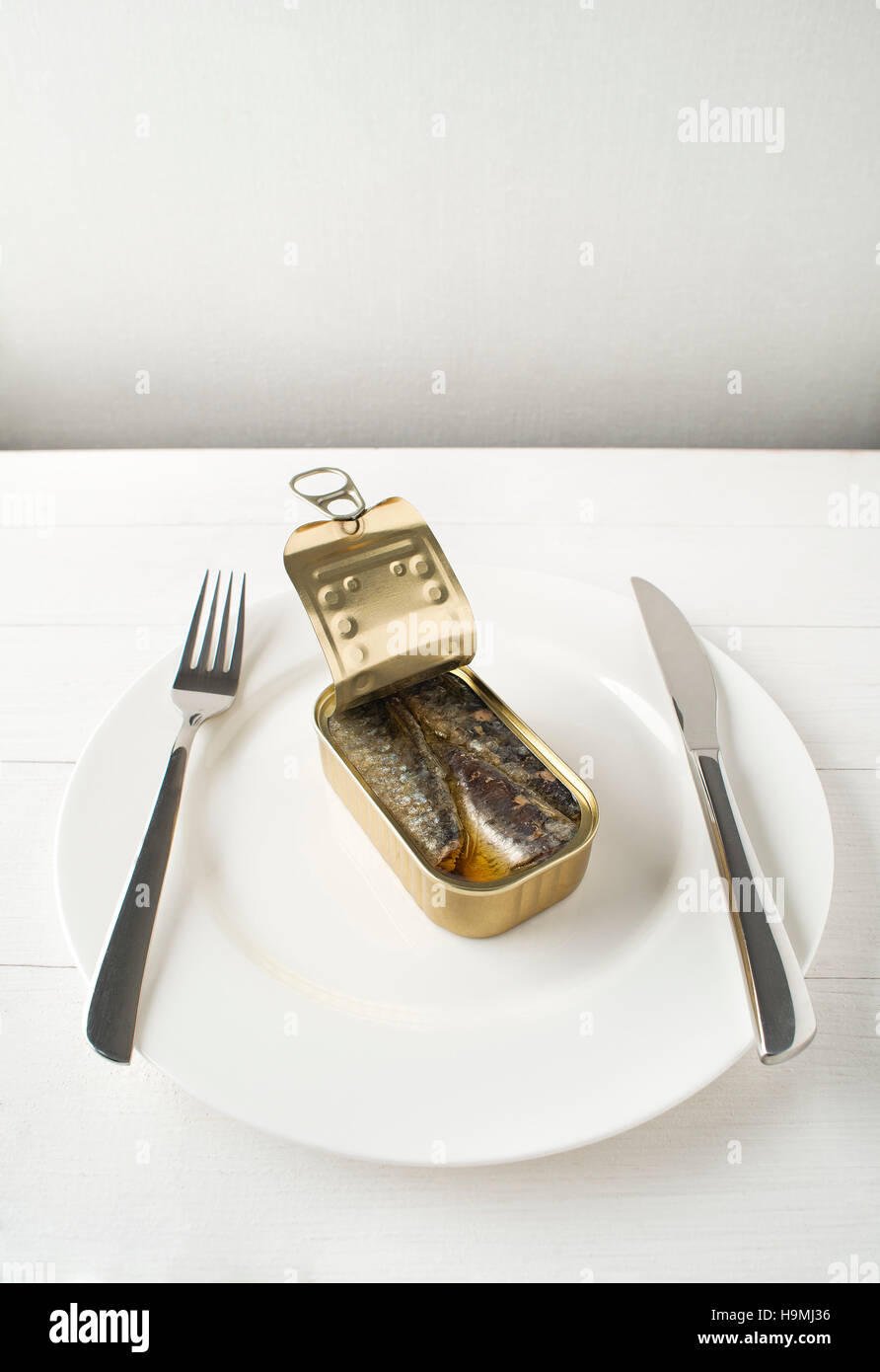 Tinned sardines in olive oil on white plate conceptual shoot Stock Photo
