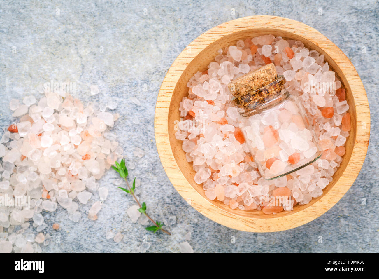 Closeup Himalayan pink salt in wooden bowl and bottle  with thym Stock Photo
