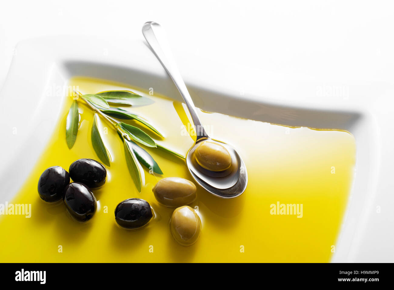 Olive oil and green olive branch in bowl Stock Photo - Alamy
