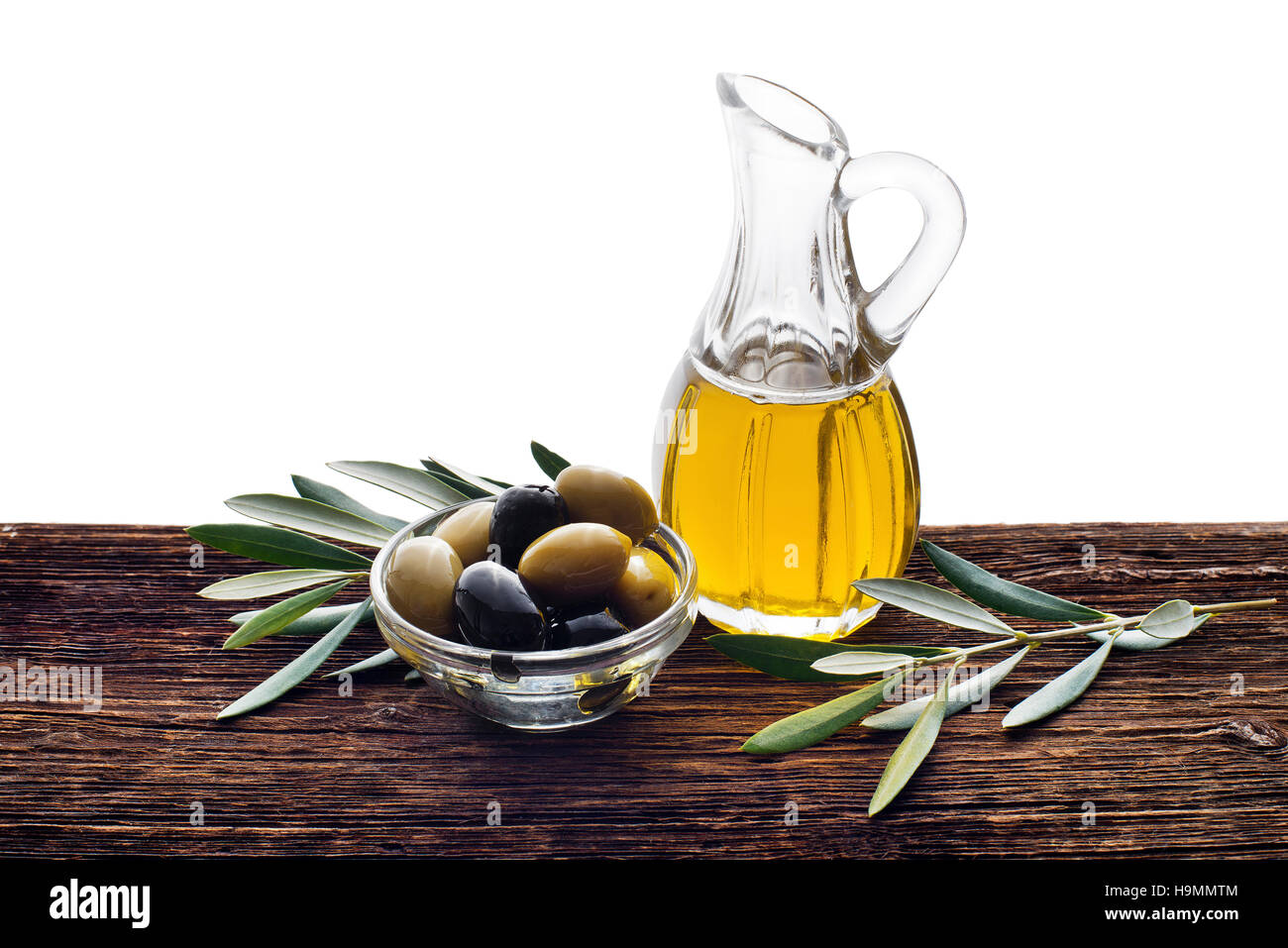 Glass bottle of premium virgin olive oil and some olives with leaves on ...