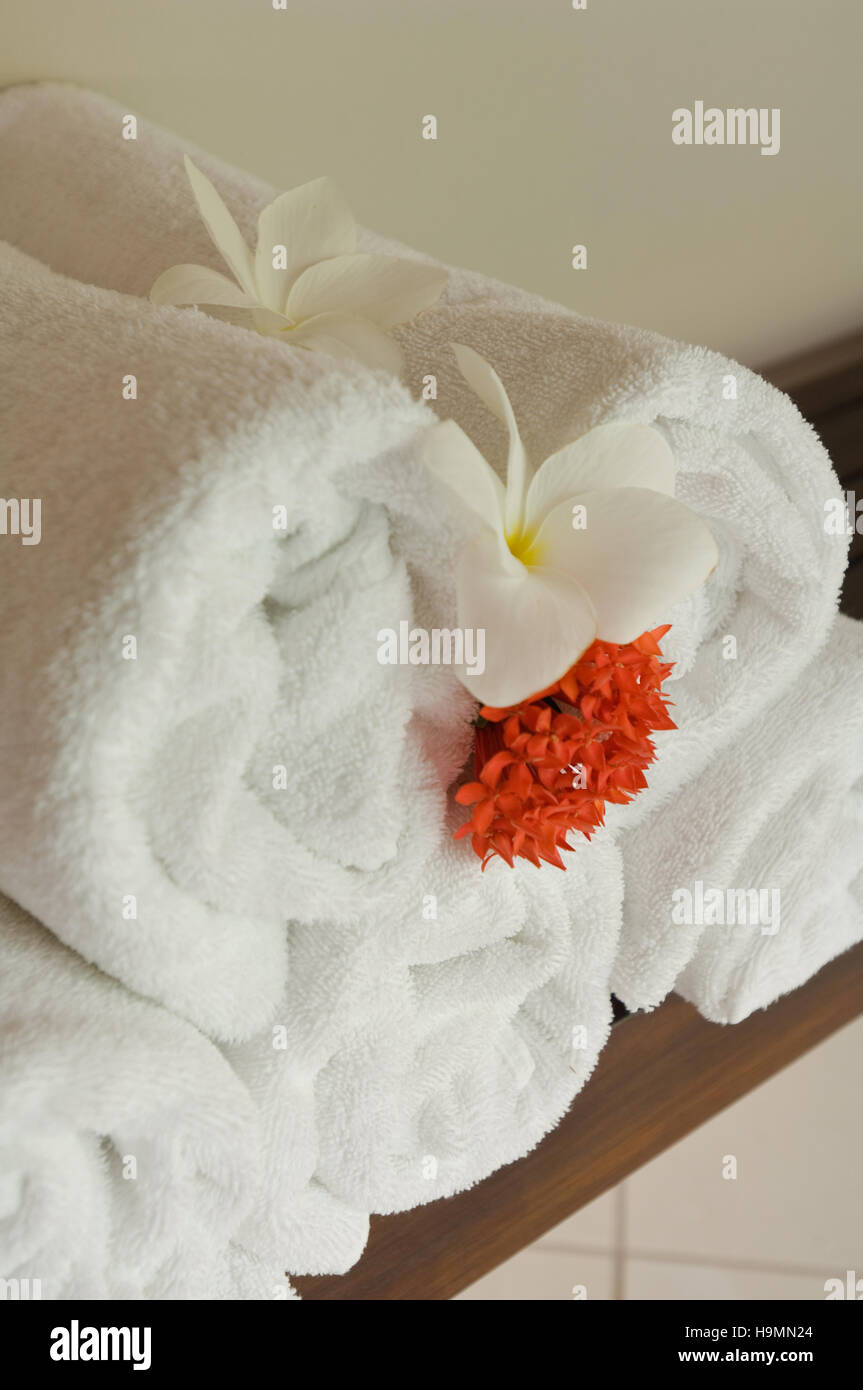 Rolled towels with cut flowerheads in Santa Lucia, spa resort, hotel and therapy centre, Caribbean Stock Photo