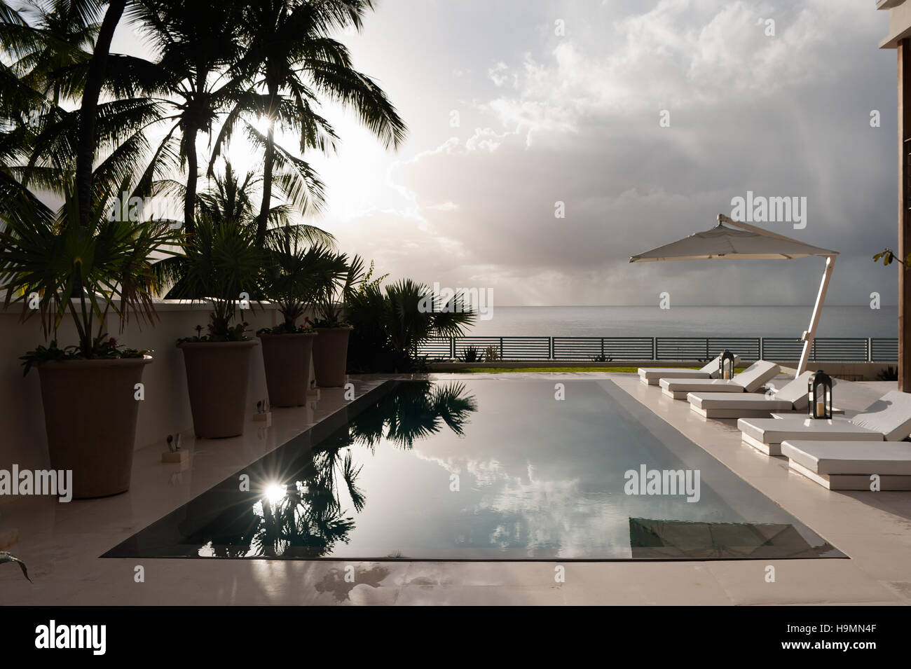 Swimming pool with reflection of sky and view to sea at dusk, Barbados, West Indies, Caribbean Stock Photo