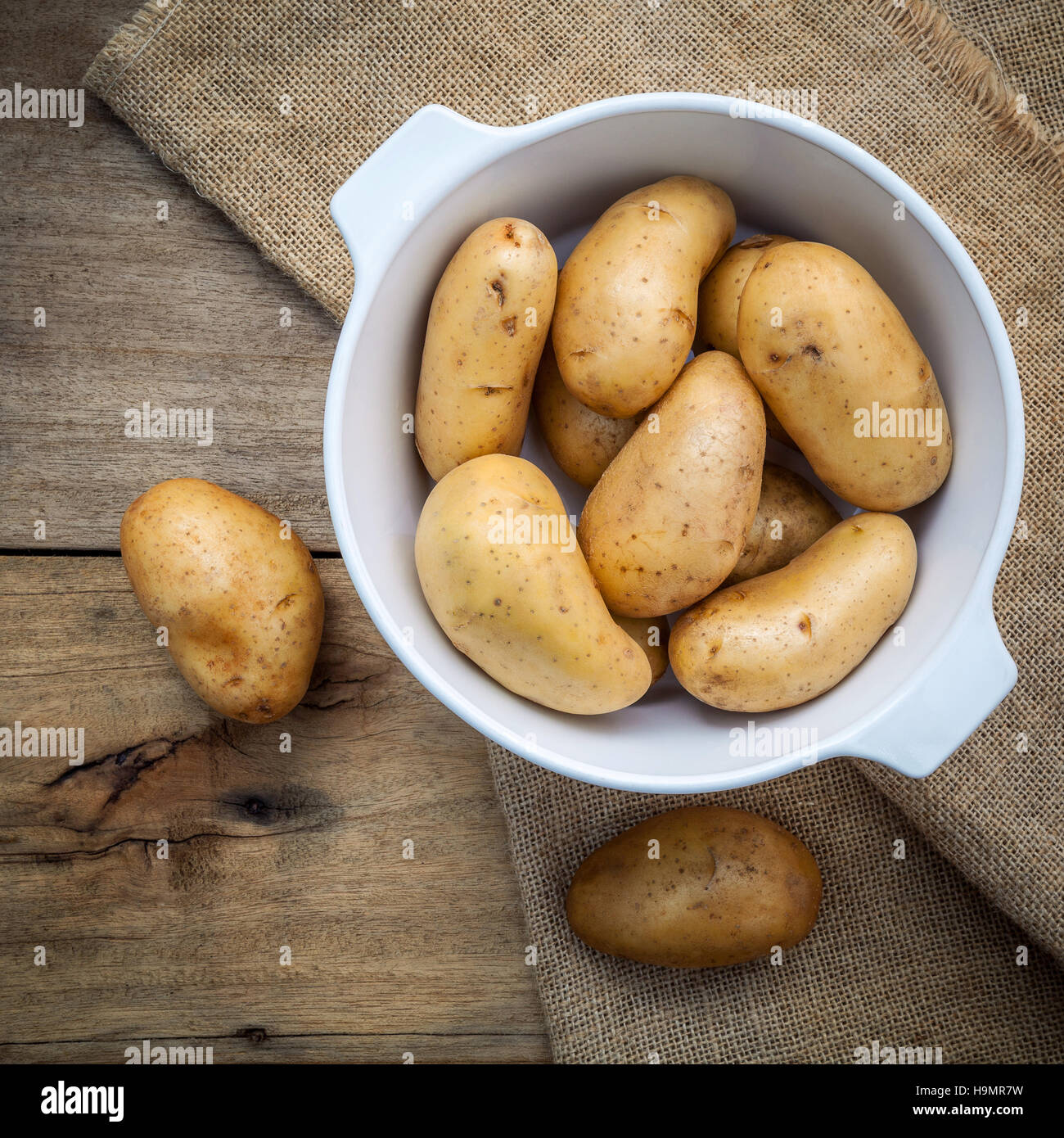 Composition of fresh organic potatoes in white ceramic bowl on h Stock Photo