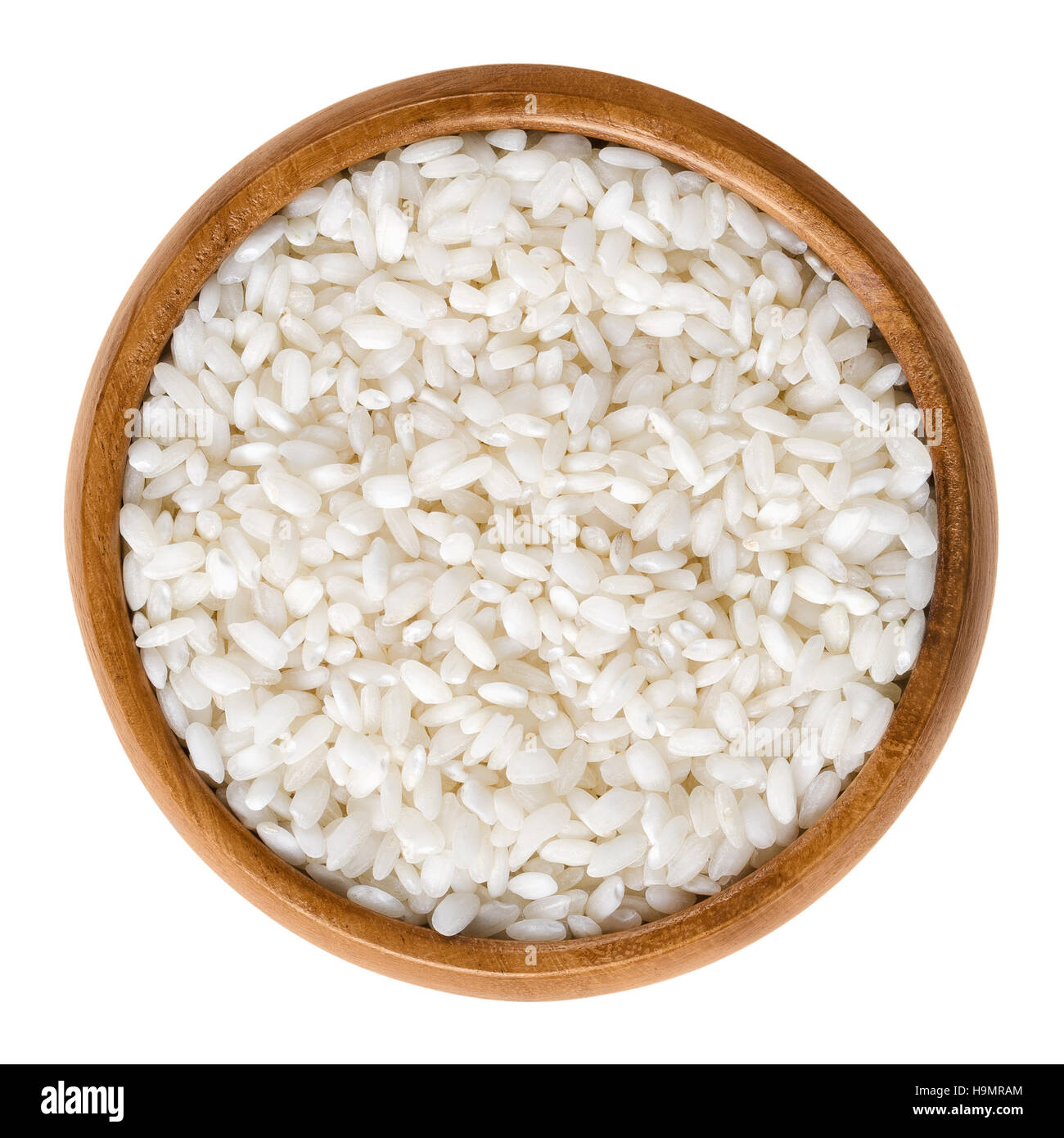 Arborio rice in wooden bowl. Italian short-grain rice with rounded grains and higher starch content, used for risotto. Stock Photo