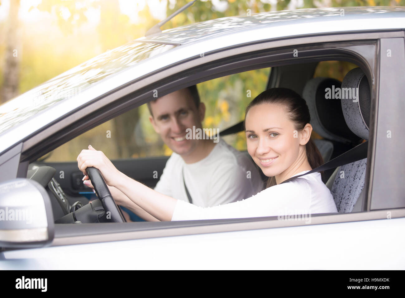 Young woman driving, a man sitting near in the car Stock Photo