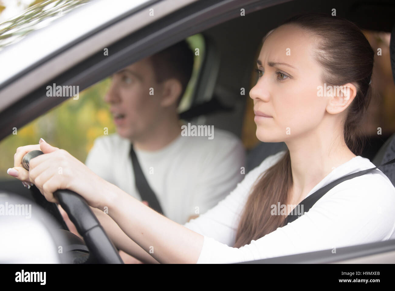 Young serious woman driving a car, man sitting aside Stock Photo
