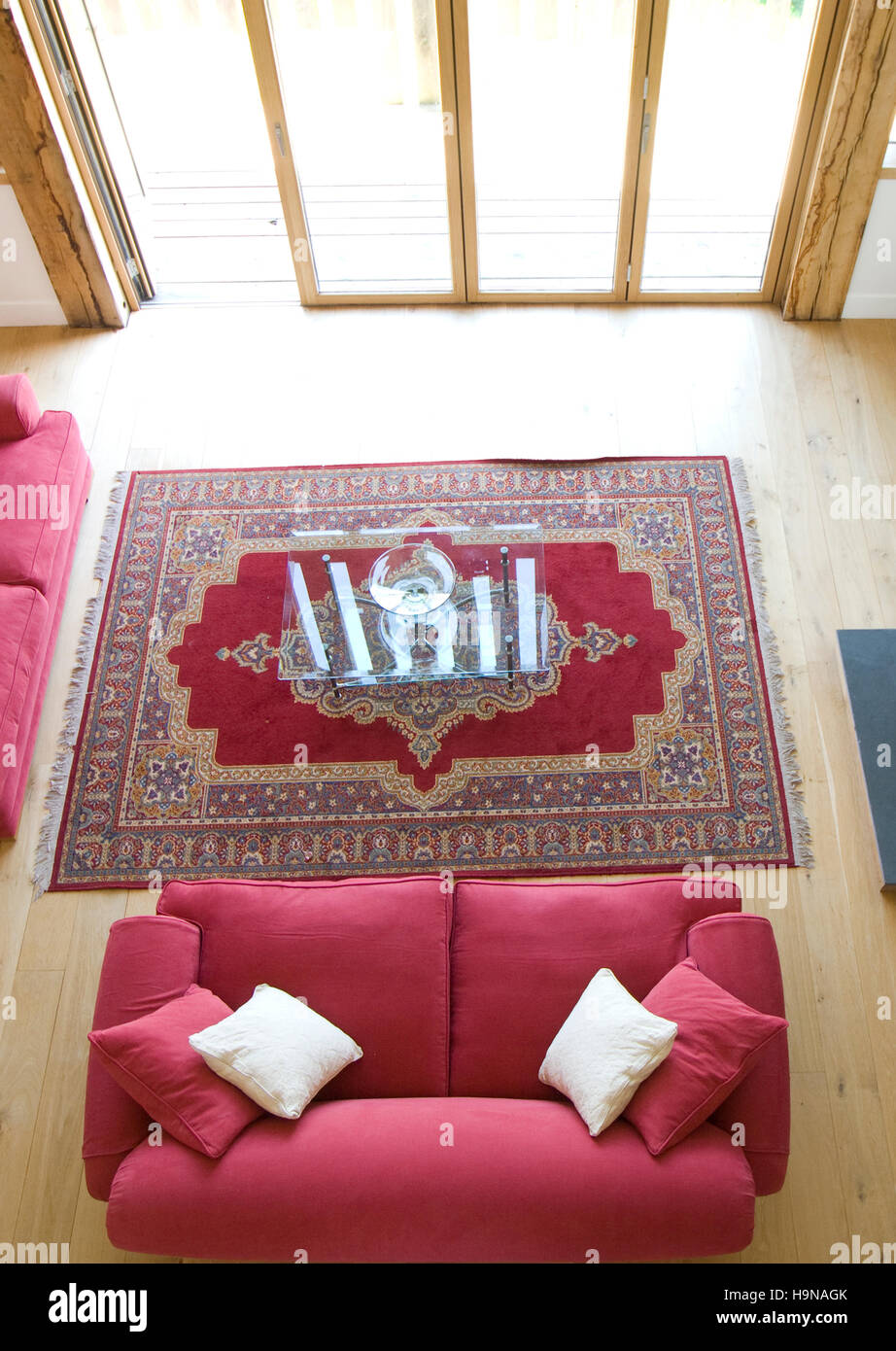 Red sofa in front of open doors, wooden floors. Stock Photo