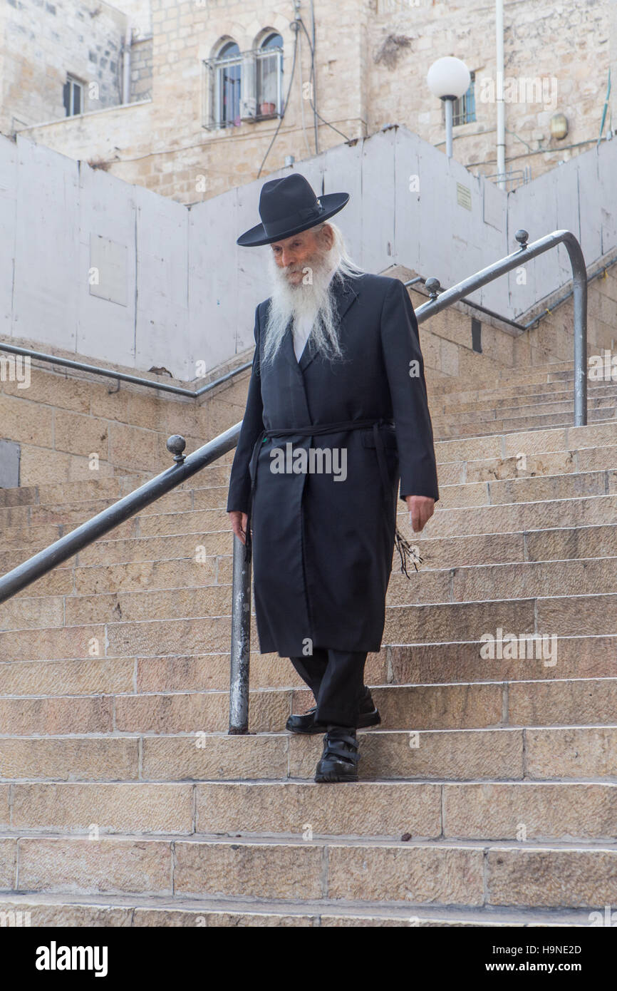 jewish man in black outfit and long white beard walking down steps Stock Photo