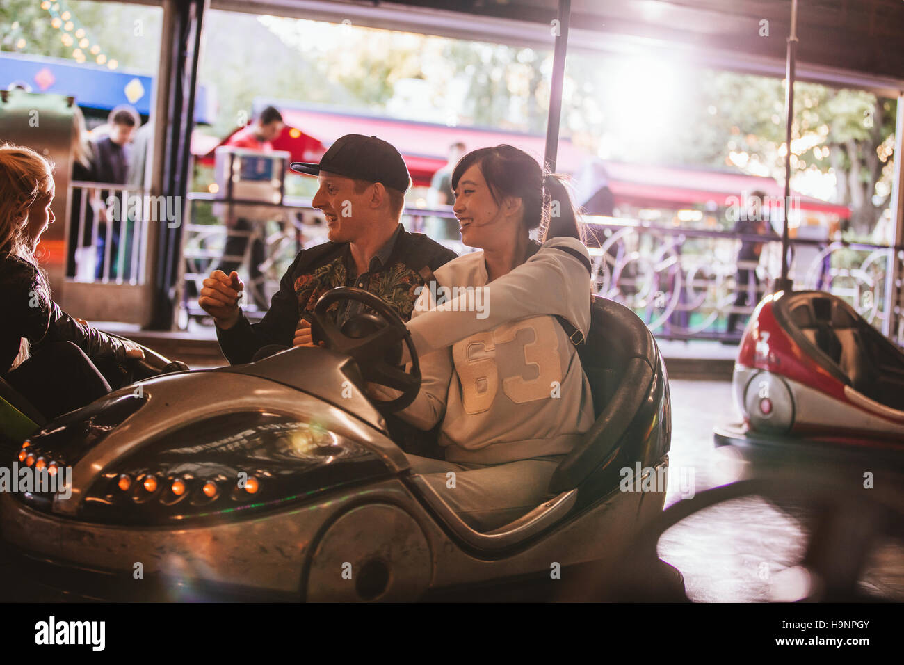 Friends on bumper car ride in amusement park. Young man and woman having fun with bumper cars at fairground. Stock Photo