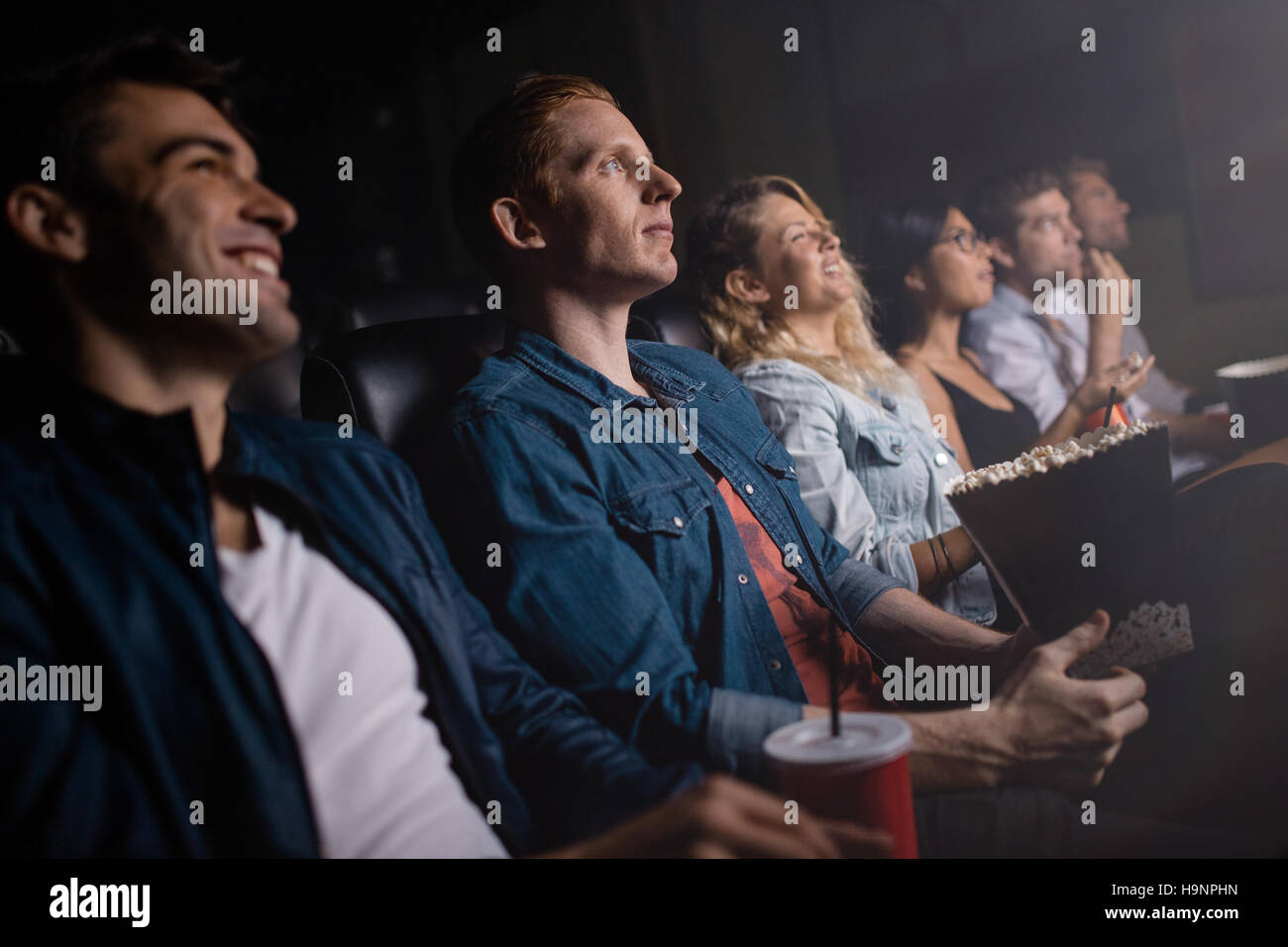 Group of people in theater watching movie. Young man with friends in cinema. Stock Photo