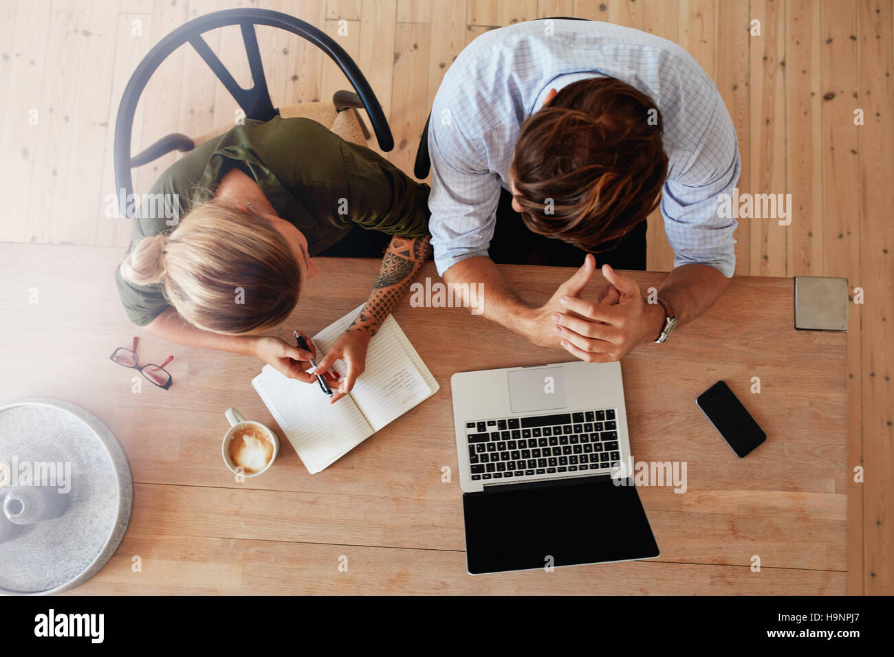 Top view of man and woman sitting at table and working. Two people working together on laptop. Stock Photo