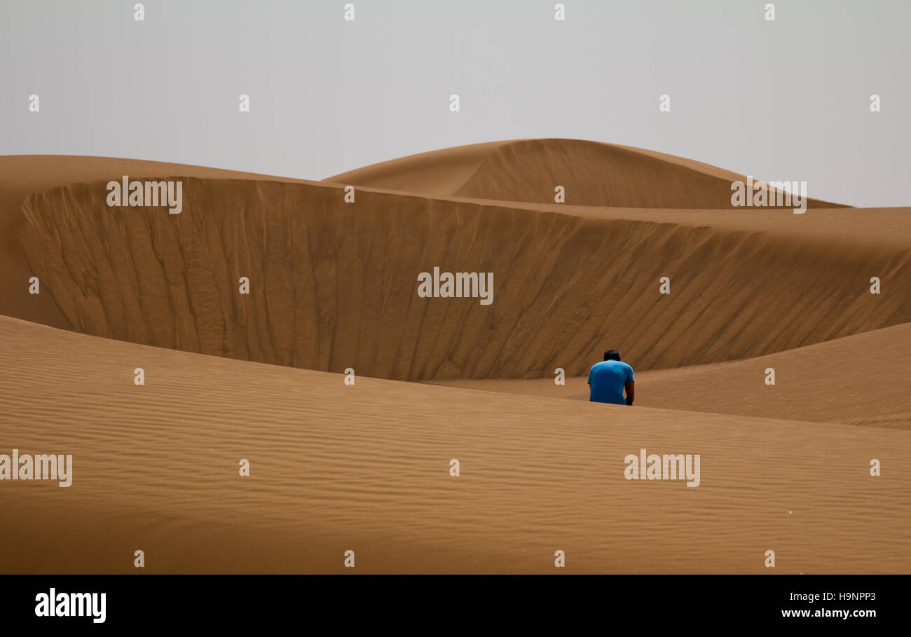 A disappointed man sitting alone in a desert in Dubai, UAE Stock Photo