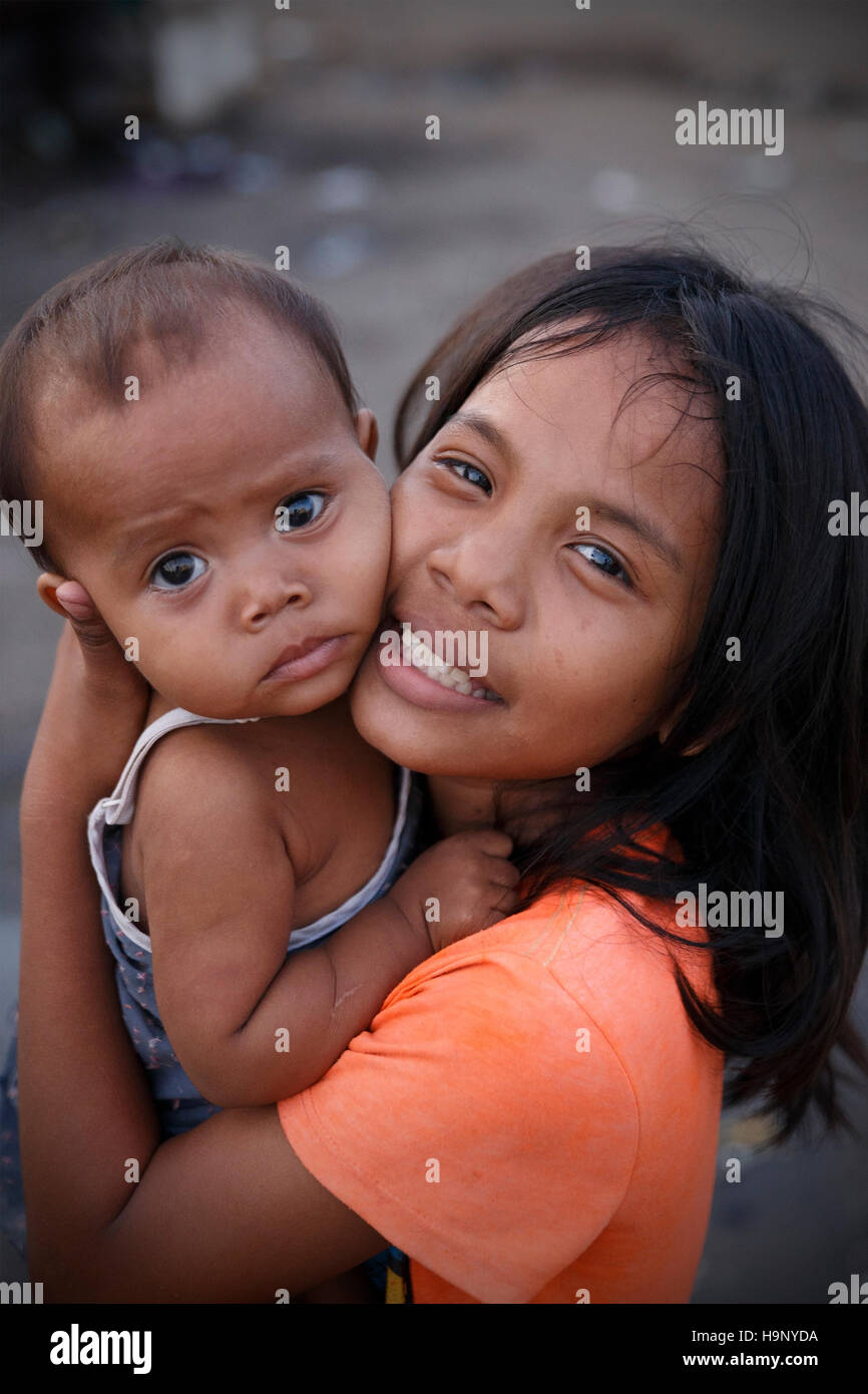 CEBU,PHILIPPINES-OCTOBER 18,2016: Little girl takes care of her little brother on the streets of the carbon market on October 18, Cebu,Philippines. Stock Photo