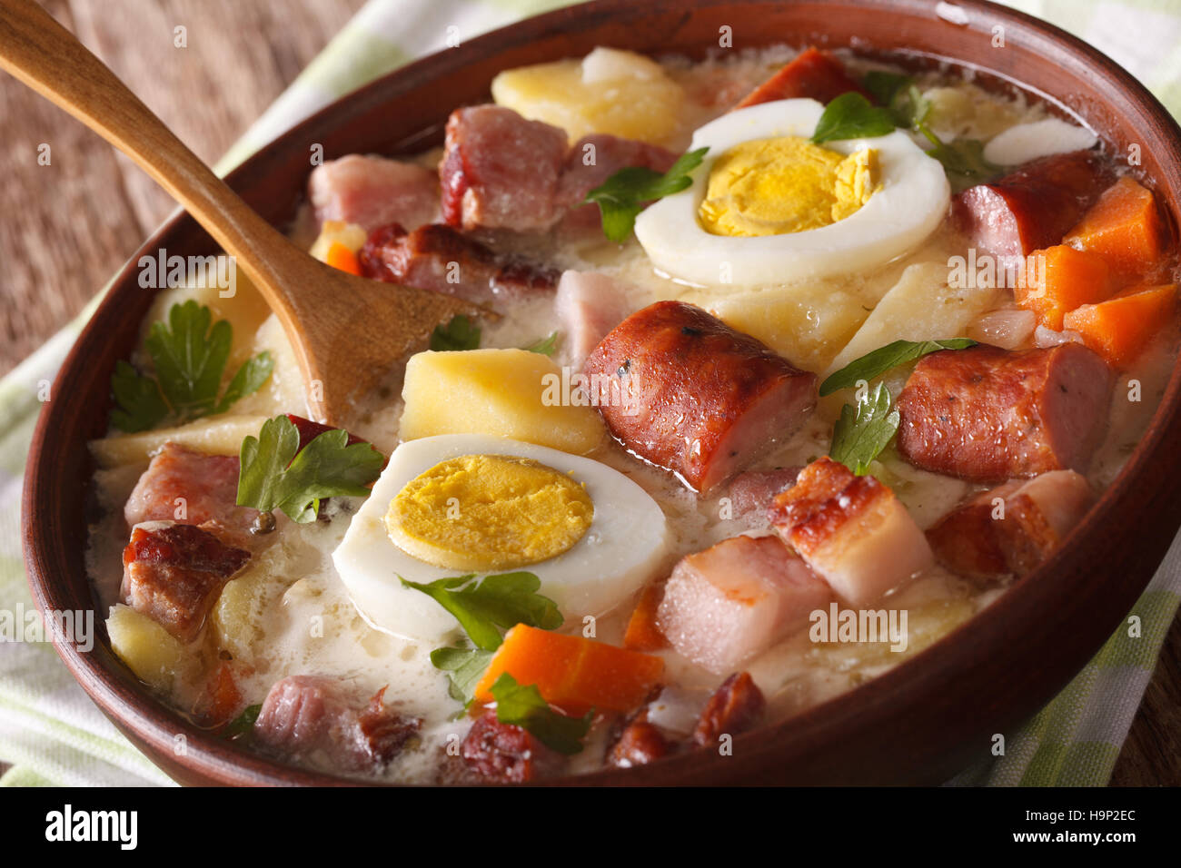 Hot Polish Zurek soup with vegetables, sausage and eggs in a bowl macro, horizontal Stock Photo