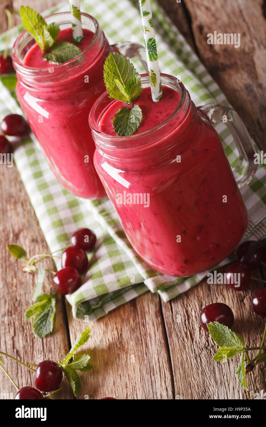 Cherry milk smoothie with a straw in a glass jar closeup on the table