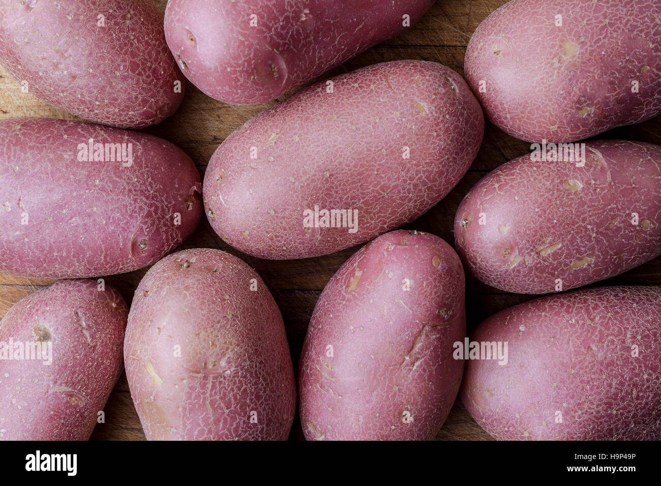 Red big imperfect potatoes on wooden cutting board from above Stock Photo