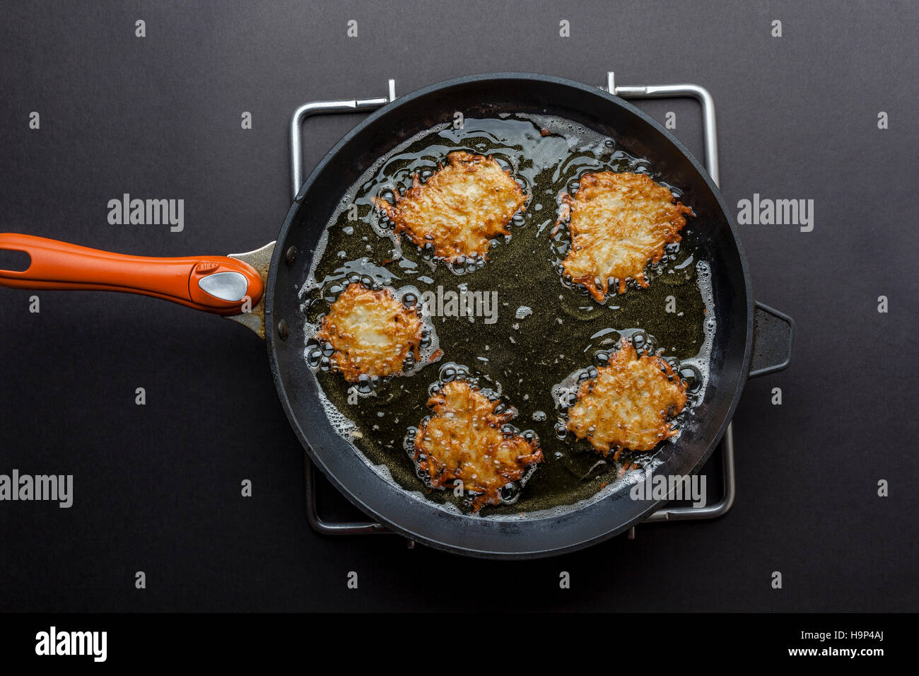 Frying latkes with ready side up in deep oil on the pan from above