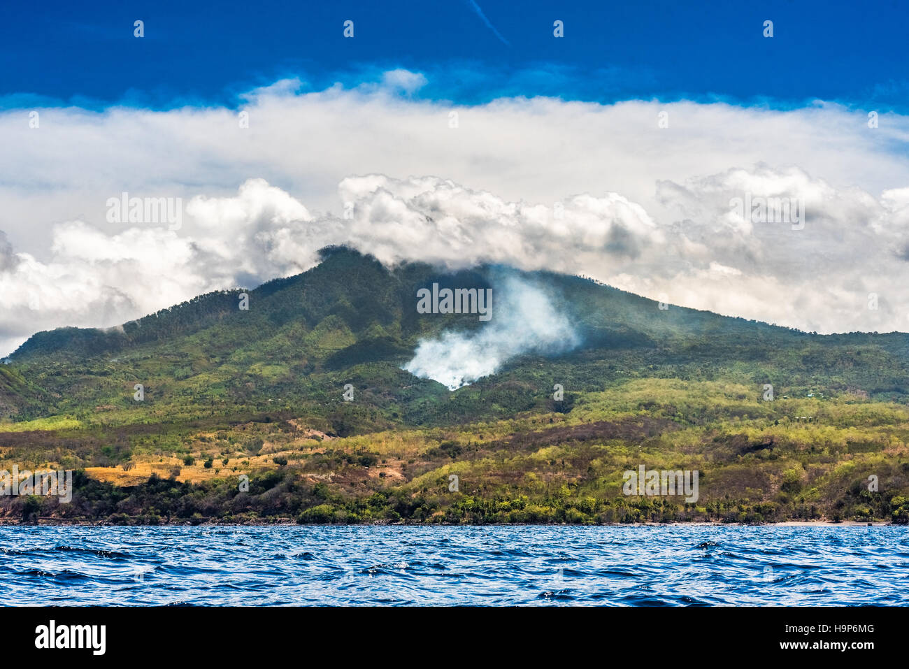 Smoke from forest fire on the slope of Mount Ili Labalekang is seen from sea water off the coast of Wulandoni, Lembata, East Nusa Tenggara, Indonesia. Stock Photo