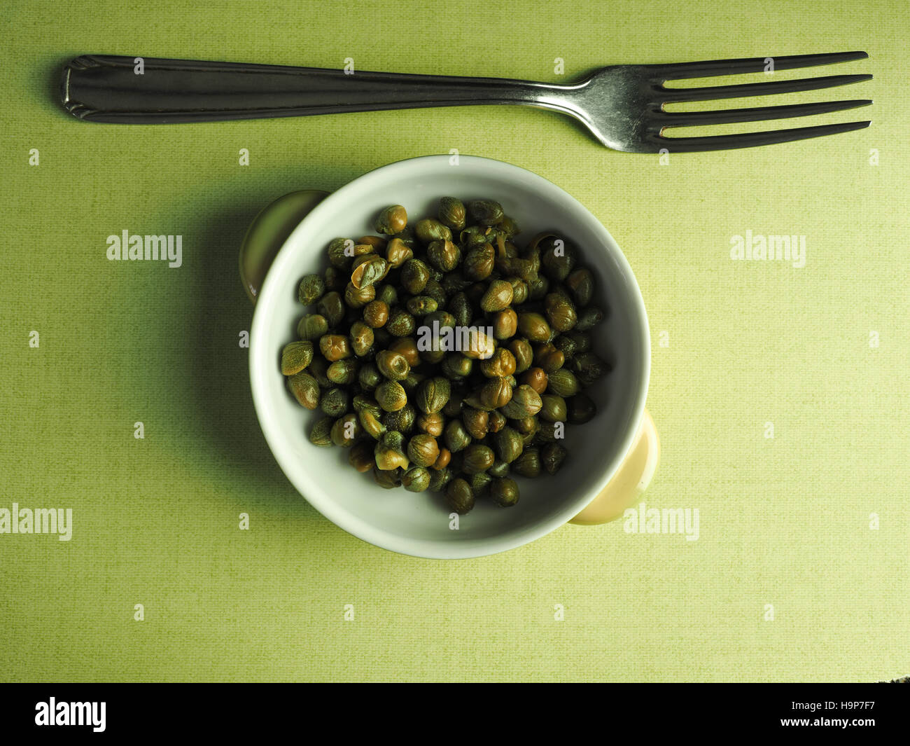 Capers in a rustic bowl on a green table cloth, top view Stock Photo ...