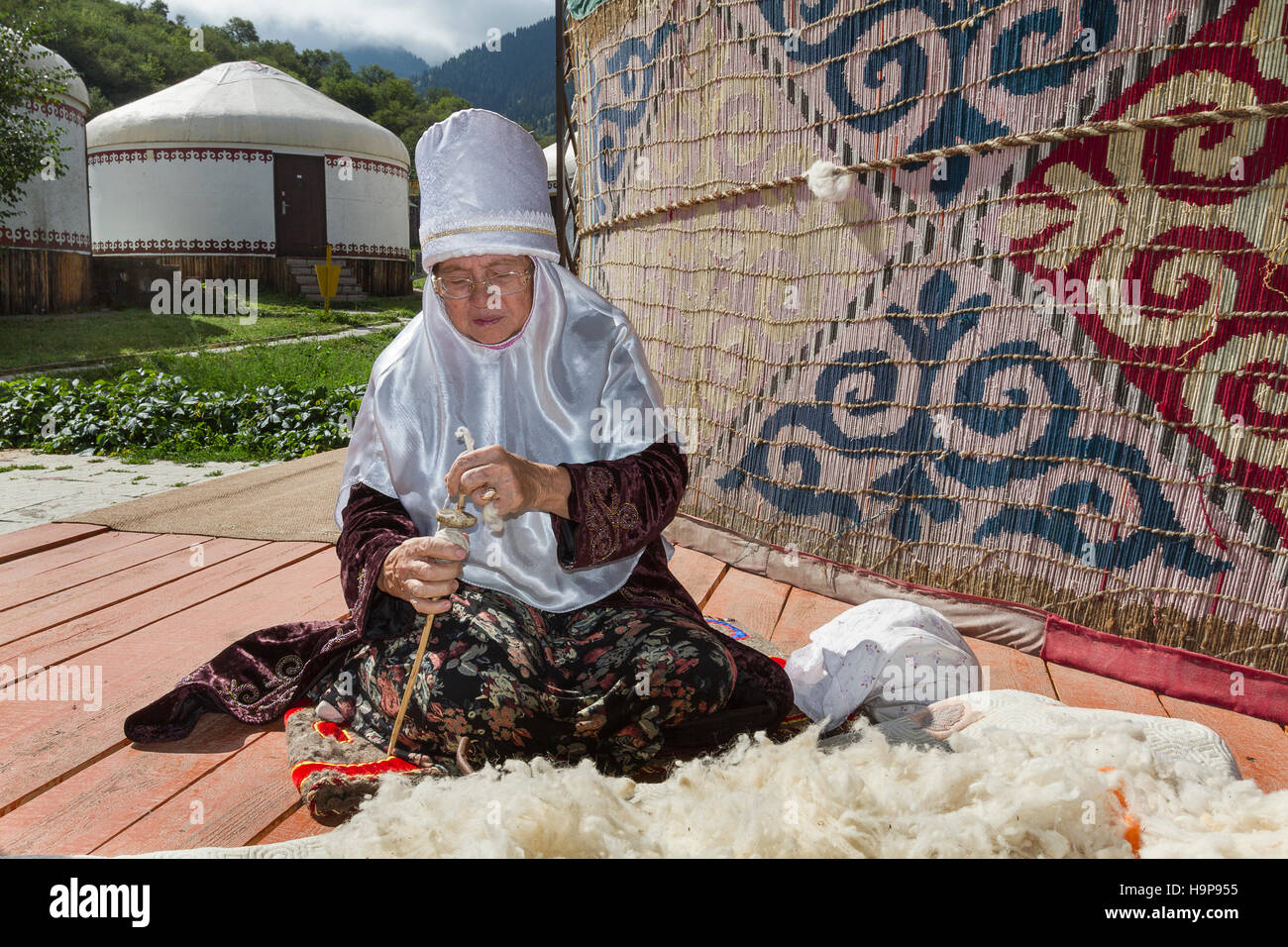 Kazakh elderly lady in local nomadic dress spinning the wool. Stock Photo