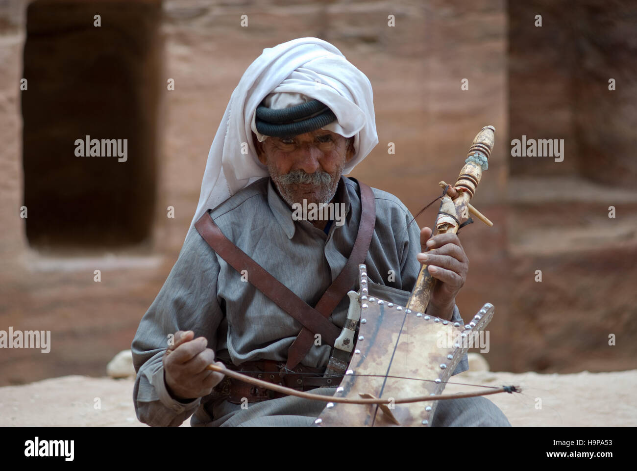 Bedouin senior man playing stringed instrument at the ancient site of Petra in Jordan Stock Photo