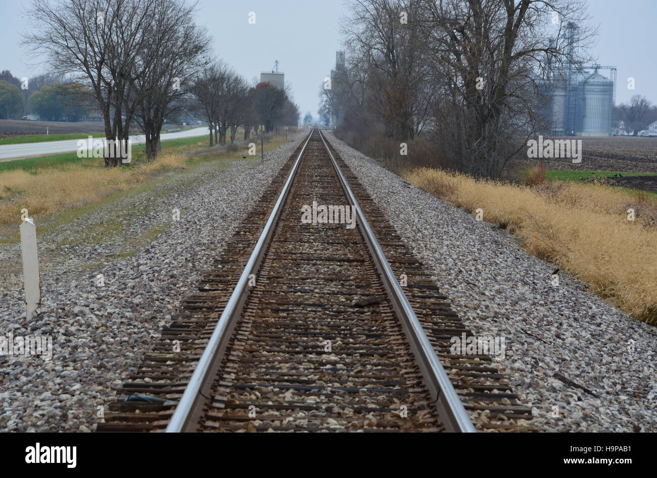 Rail road tracks stretch off into the distance under cold gray November skies in the Midwestern United States. Stock Photo