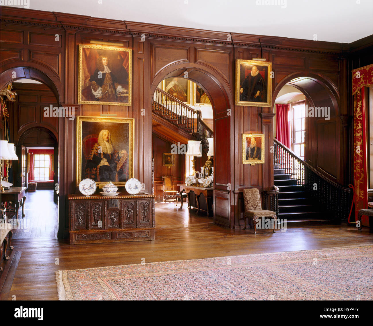 View of the entrance Hall at Antony showing the staircase, three arches , stained oak panelling, paintings and early C18th oak chest. Stock Photo