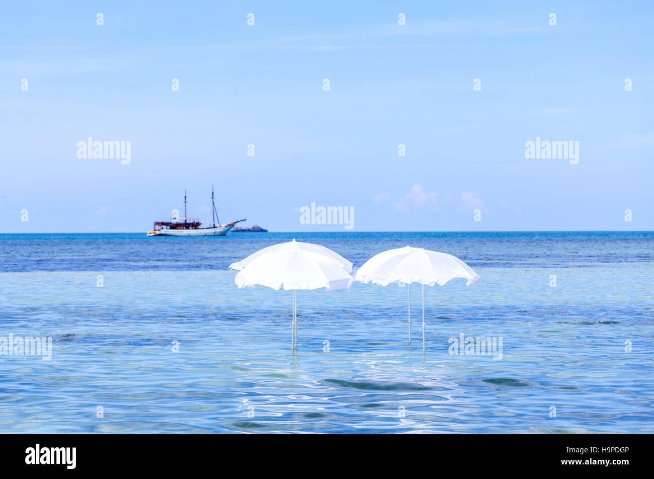 White umbrella on summer tropical beach with sailing boat Stock Photo