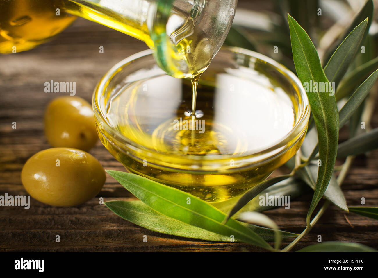 Bottle pouring virgin olive oil in a bowl close up Stock Photo