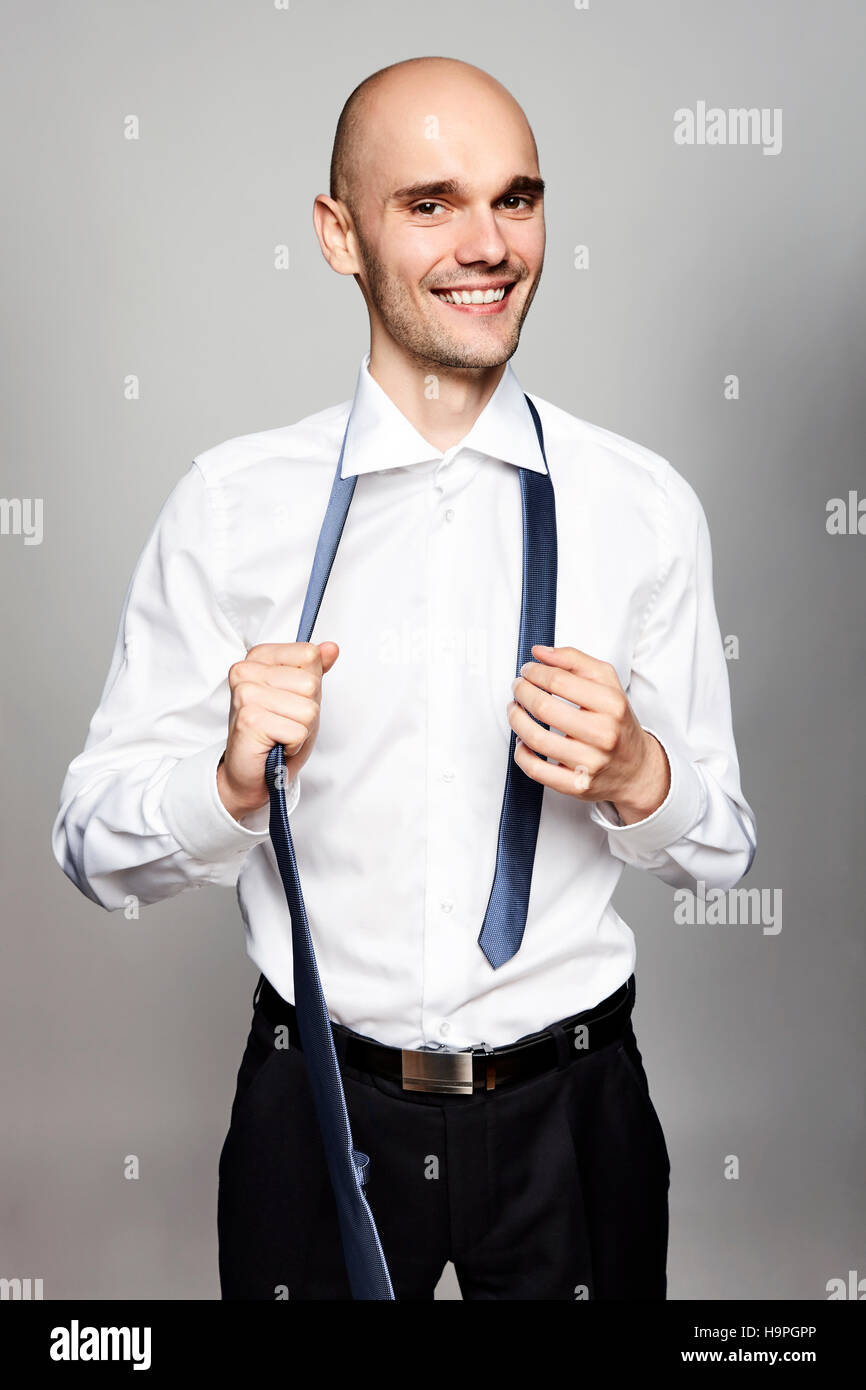 Portrait of young smiling man taking off a tie. Stock Photo