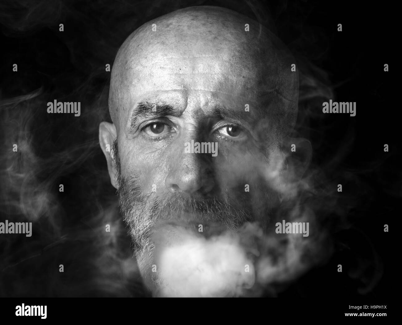 Man blowing smoke, portrait in low key and black and white Stock Photo