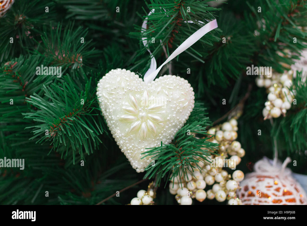 Christmas and New Year seasonal decoration, green tree branches with white heart and golden ornaments Stock Photo