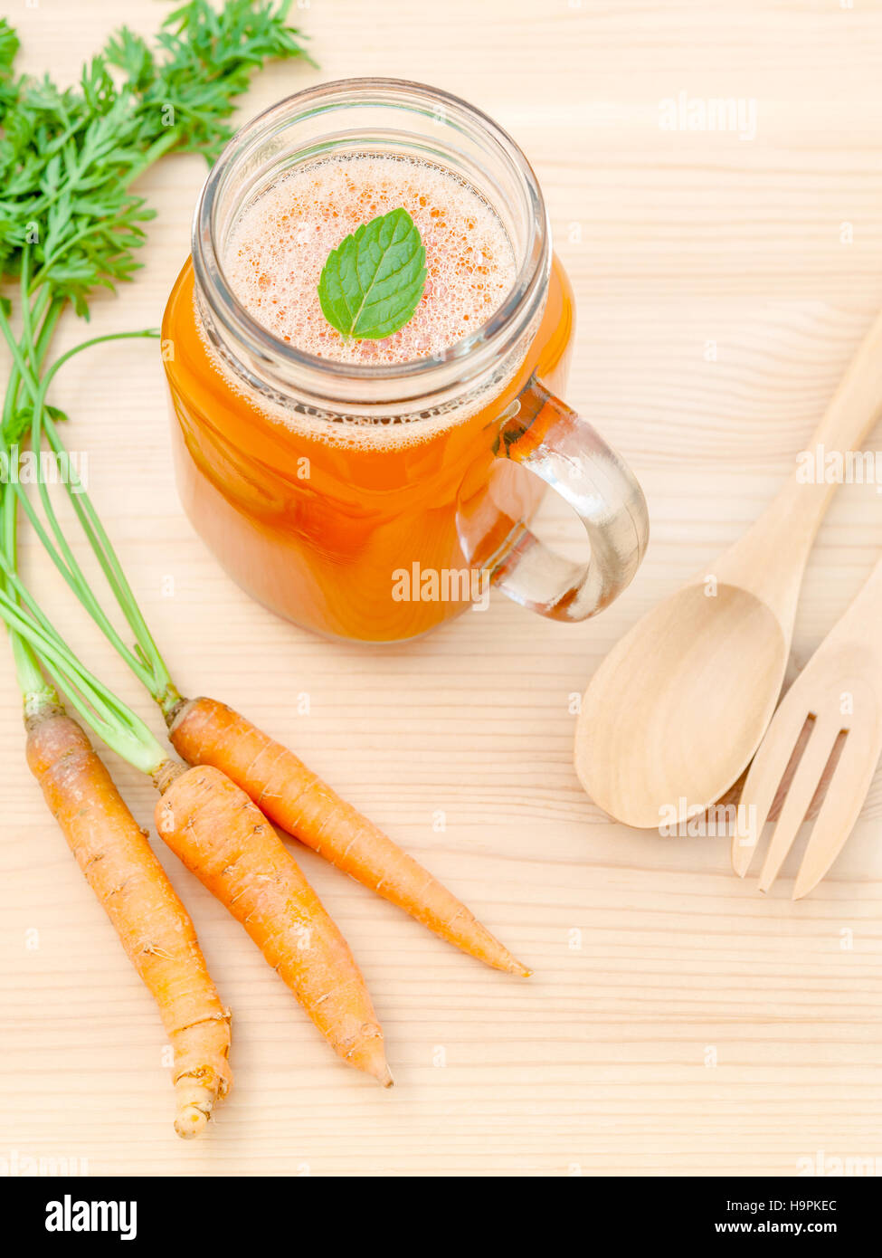 Glasses of carrot juice with carrot roots on wooden background.G Stock Photo