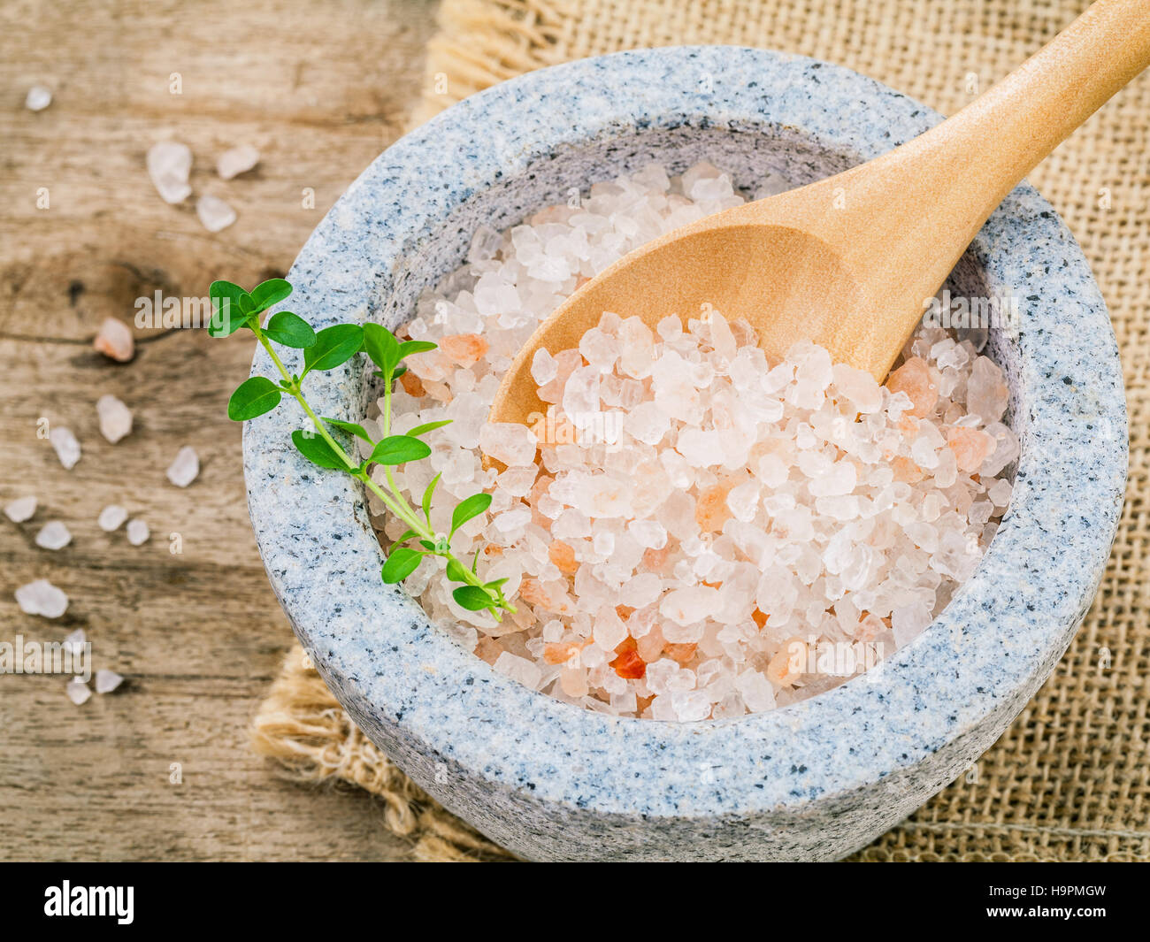 Himalayan pink salt in mortar with thyme on hemp sack background Stock Photo