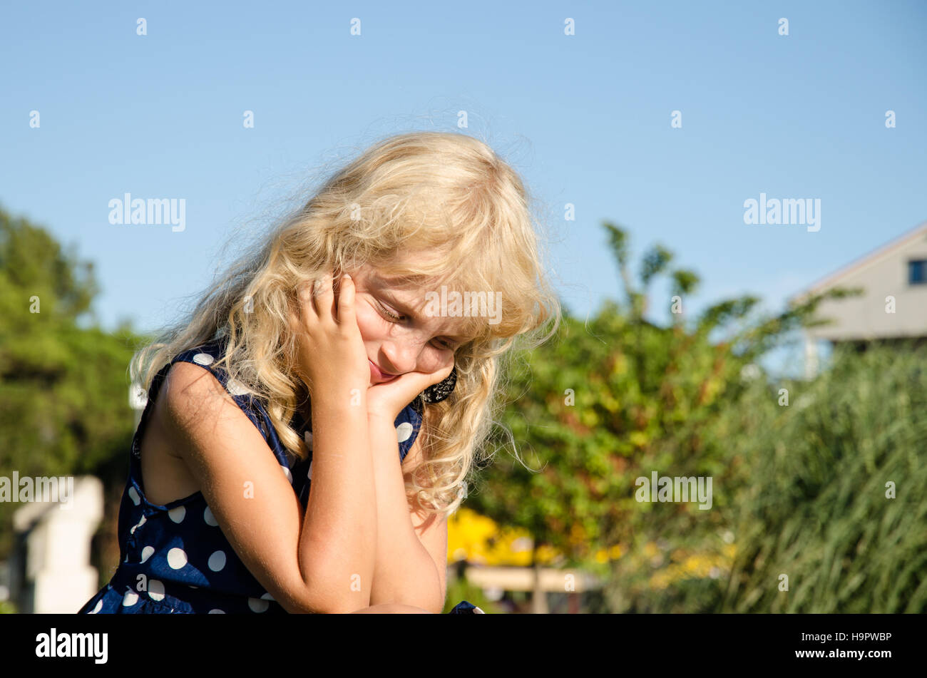 little blond girl in thinking posture holding her head with hands Stock ...