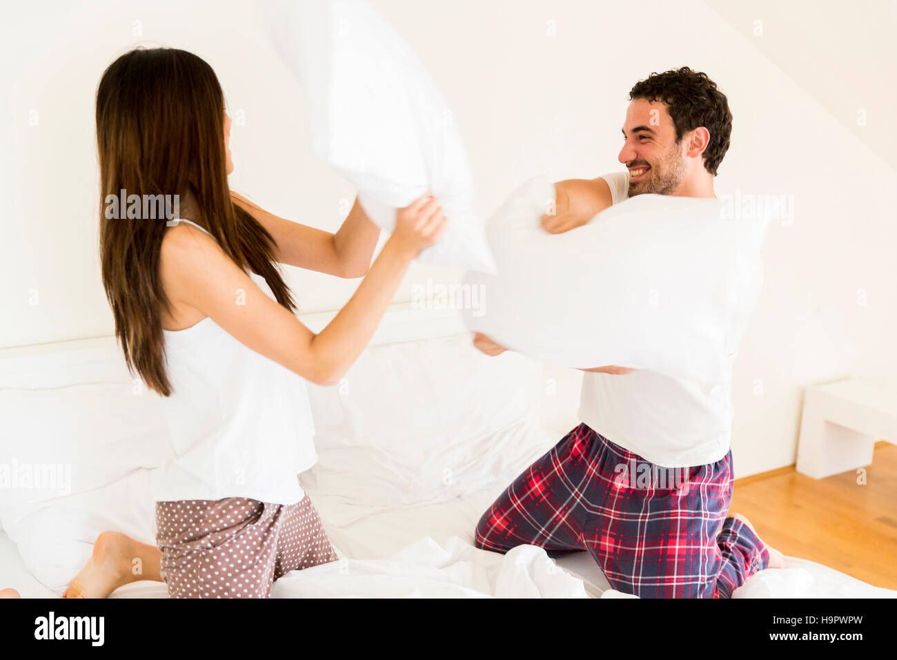 Couple having fun with a pillow fight in bed Stock Photo