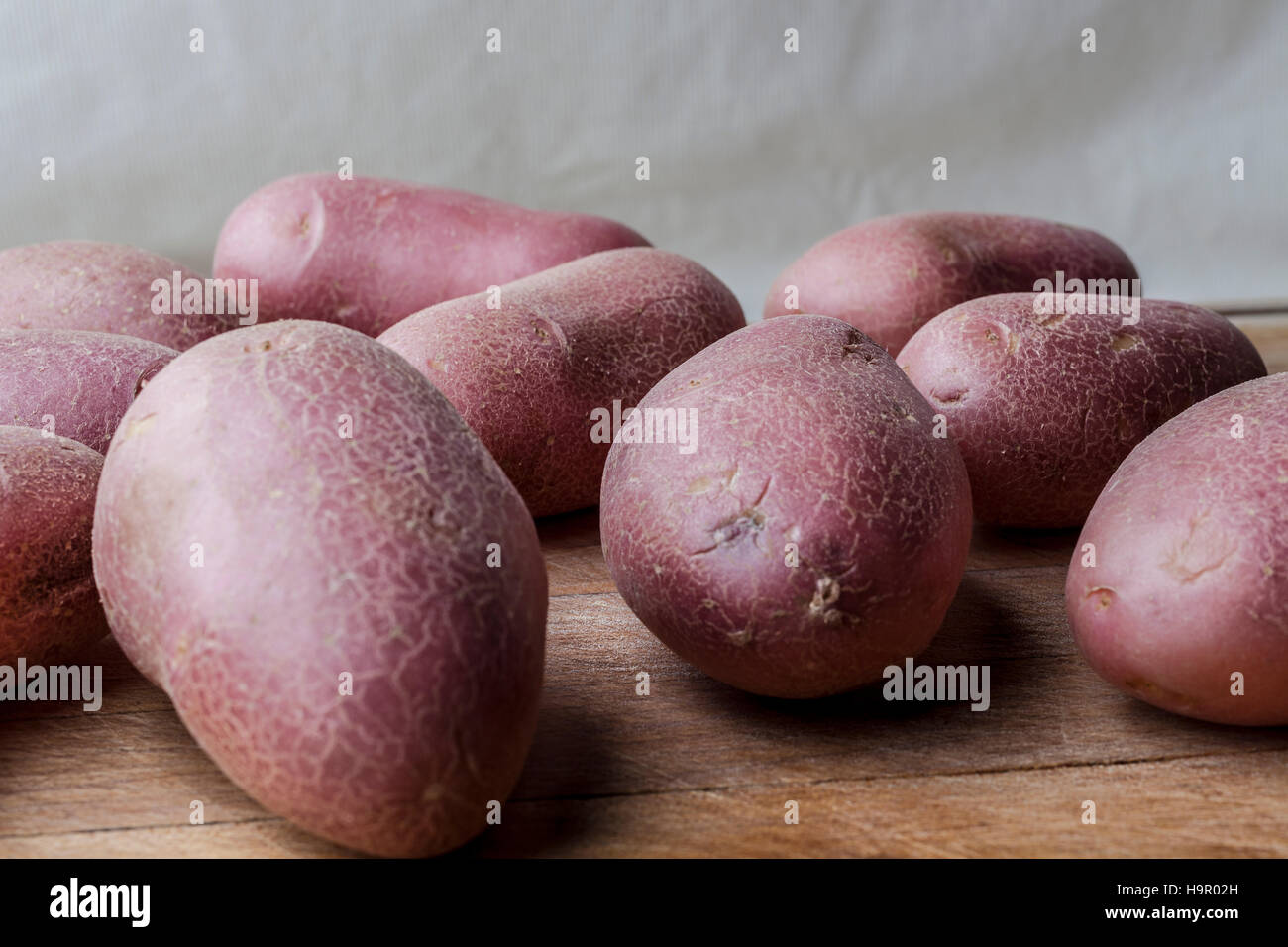 Red big imperfect potatoes on wooden cutting board Stock Photo